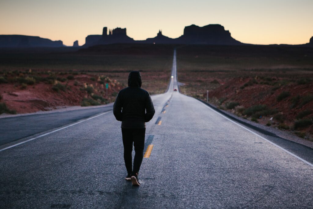 a woman walking down a long road is finding the motivation to keep going. 